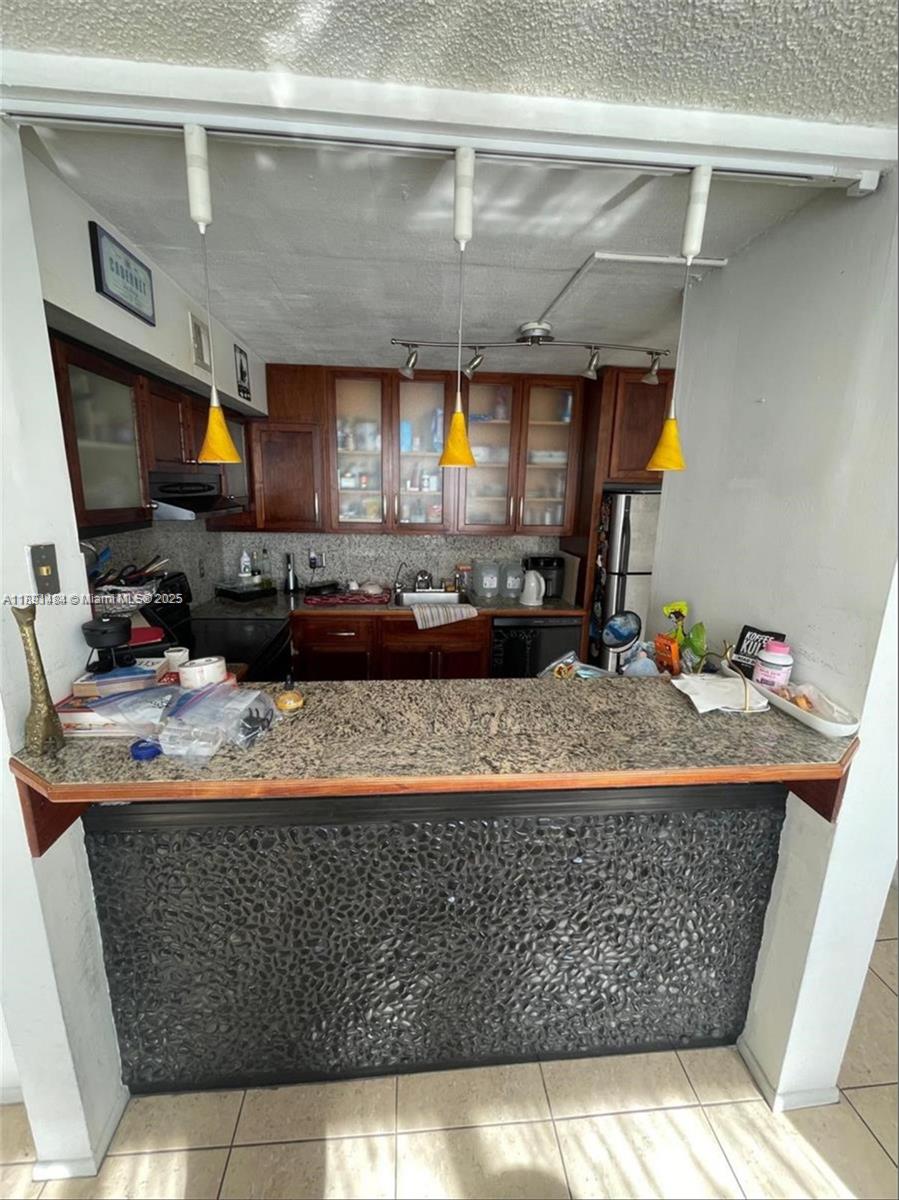 A kitchen features dark wood cabinets, granite countertops, and a stone-faced breakfast bar — 9460 Live Oak Pl # 309, Davie FL 33324, DAVIE, FL