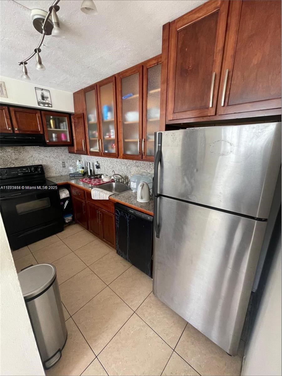 A kitchen features wooden cabinets, stainless steel appliances, a tiled floor, and granite countertops — 9460 Live Oak Pl # 309, Davie FL 33324, DAVIE, FL