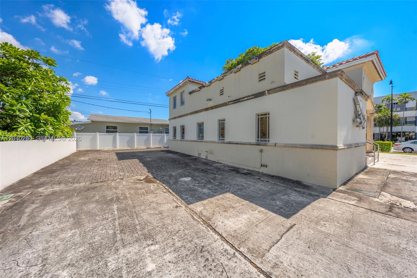The exterior of a two-story stucco building features a paved parking area and white fencing — 4201 SW 11th St, Miami FL 33134, MIAMI, FL