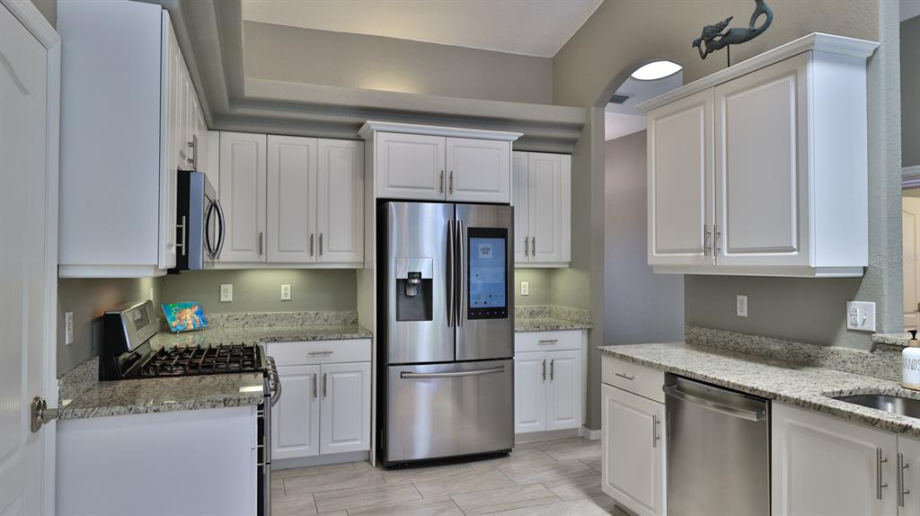 A kitchen features white cabinets, granite countertops, stainless steel appliances, and a smart refrigerator — 29 ACCLAIM AT LIONSPAW, DAYTONA BEACH, FL