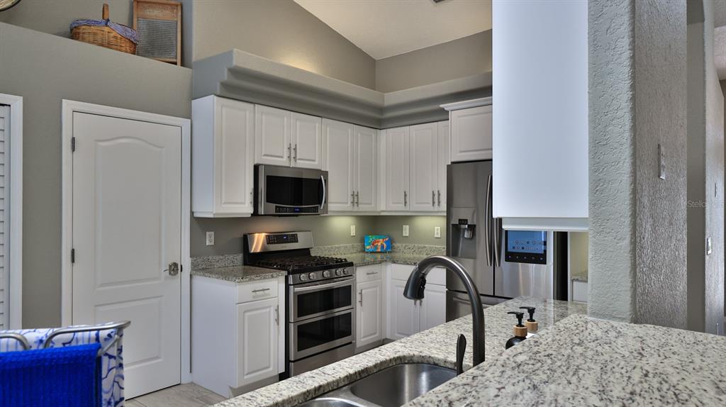 A kitchen features white cabinets, stainless steel appliances, granite countertops, and a double-basin sink — 29 ACCLAIM AT LIONSPAW, DAYTONA BEACH, FL