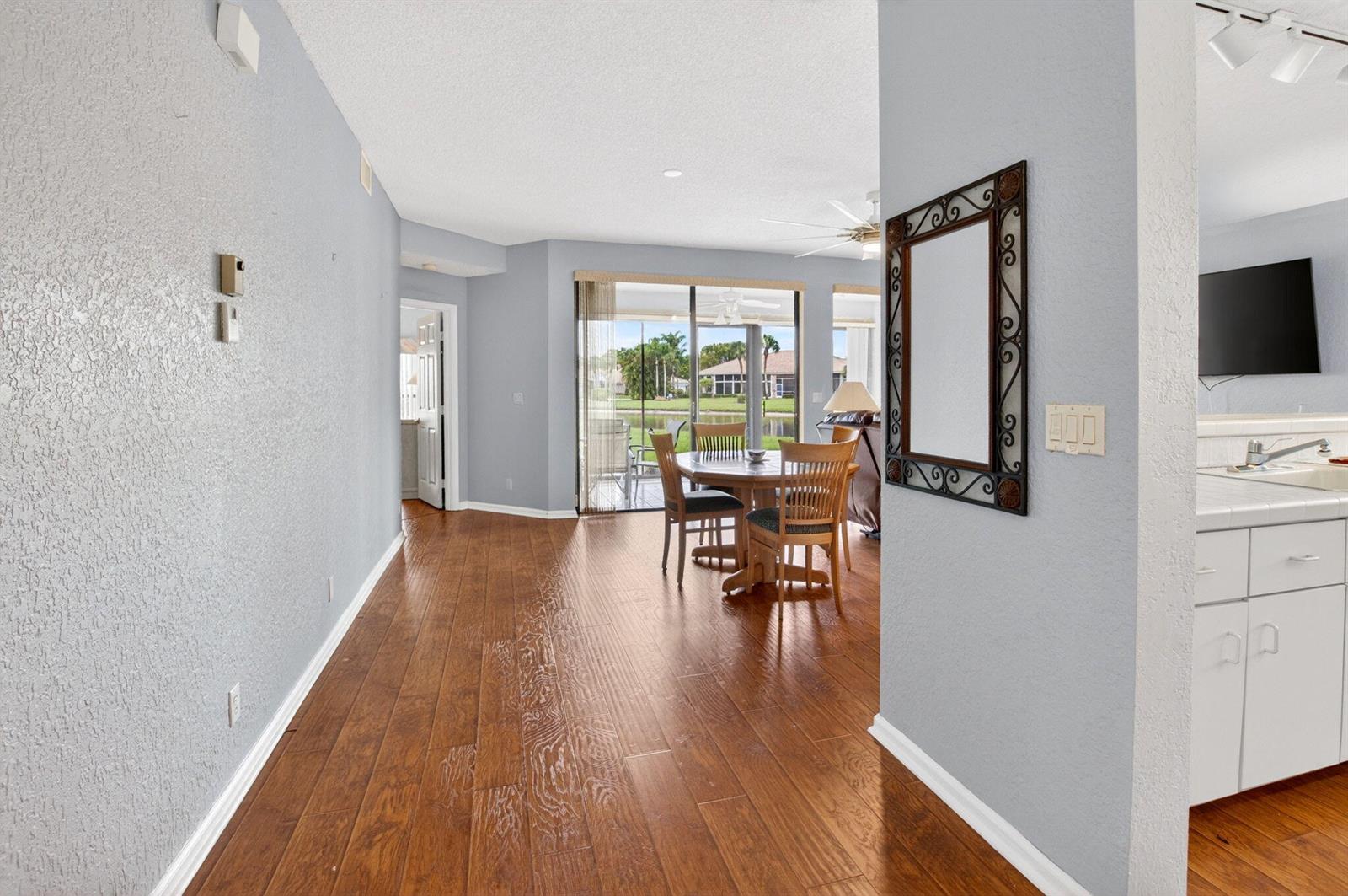 A dining area with wood flooring leads to a sliding glass door overlooking a lake — 8073 Aberdeen Drive # 102, Boynton Beach FL 33472, BOYNTON BEACH, FL