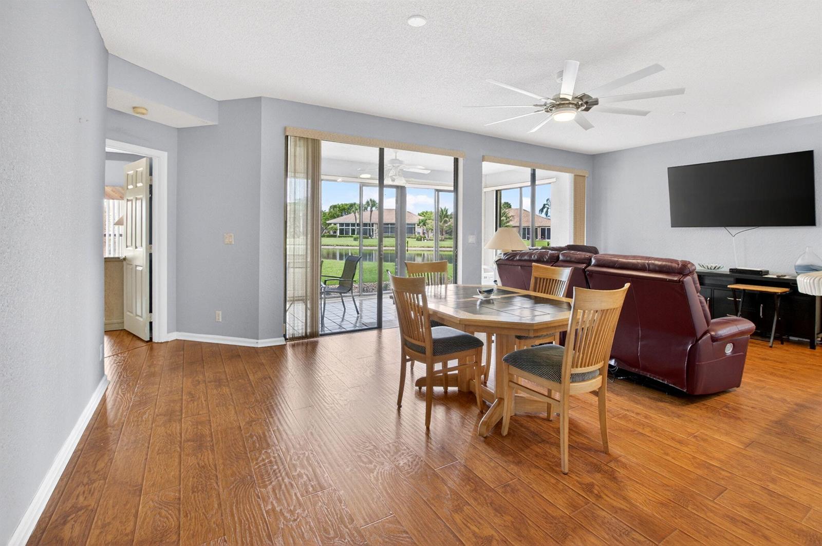 A dining area with wood flooring and a sliding glass door overlooking a lake — 8073 Aberdeen Drive # 102, Boynton Beach FL 33472, BOYNTON BEACH, FL