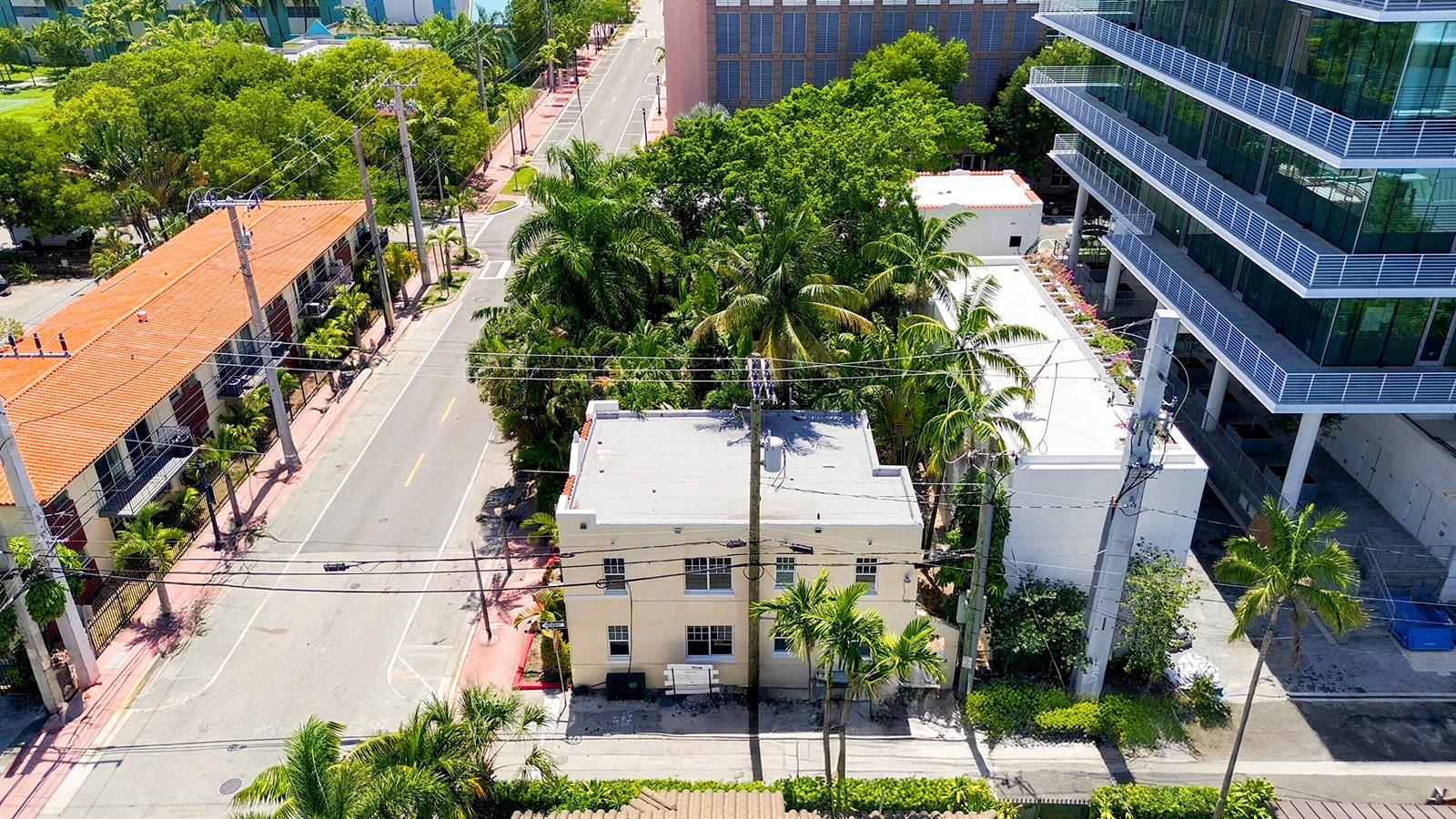 An aerial view shows a two-story beige building nestled among palm trees and urban structures — 927 4th Street, Miami Beach FL 33139, MIAMI BEACH, FL