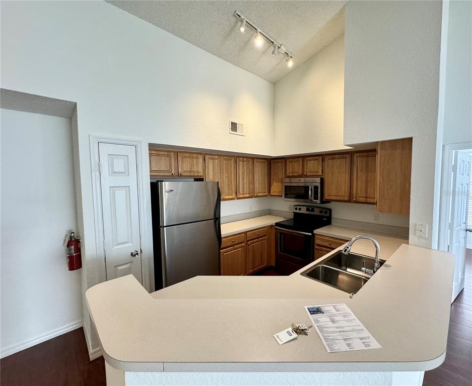 A kitchen with light wood cabinets, stainless steel appliances, and a breakfast bar — 13028 PLANTATION PARK CIRCLE UNIT 1226, ORLANDO, FL