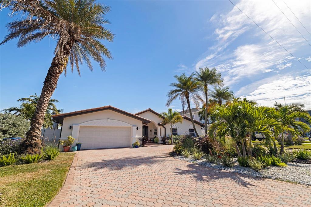 A single-story house with a paved driveway and palm trees under a clear blue sky — 7827 9TH AVENUE S, ST PETERSBURG, FL