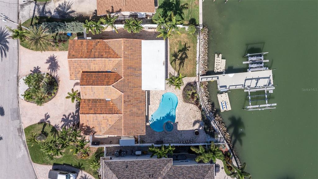 An aerial view of a waterfront house with a tiled roof, pool, and private dock — 7827 9TH AVENUE S, ST PETERSBURG, FL