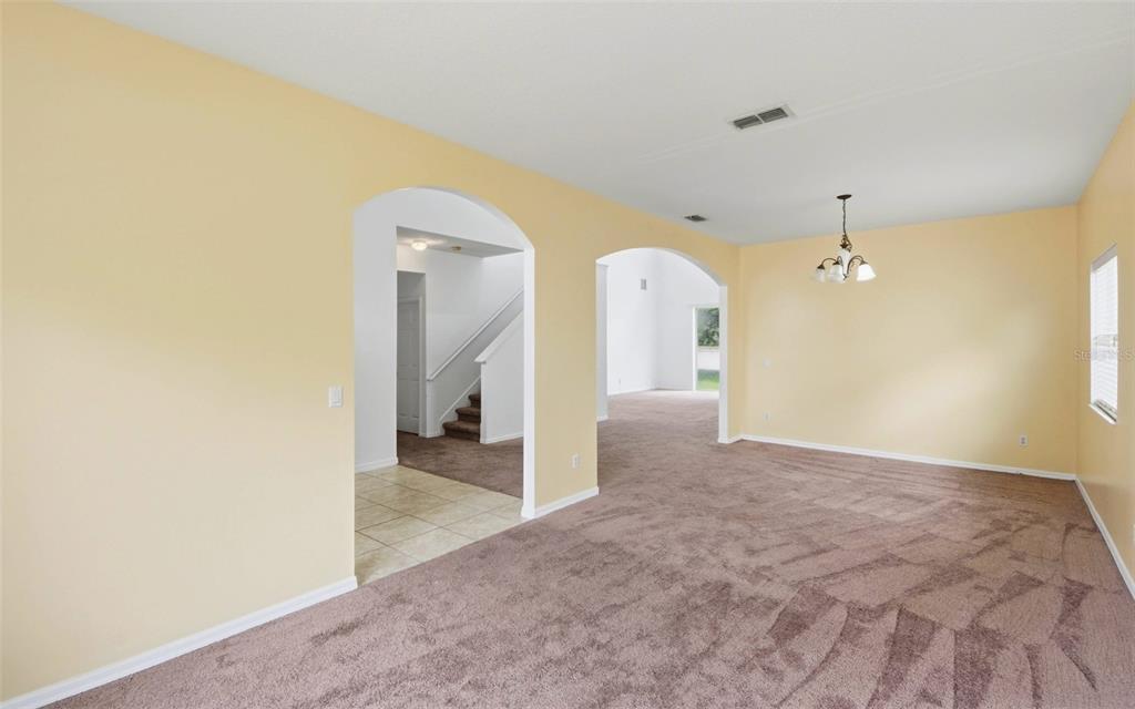 A living room with beige walls, brown carpeting, and two arched doorways leading to other areas — 2838 SWEETSPIRE CIRCLE, KISSIMMEE, FL