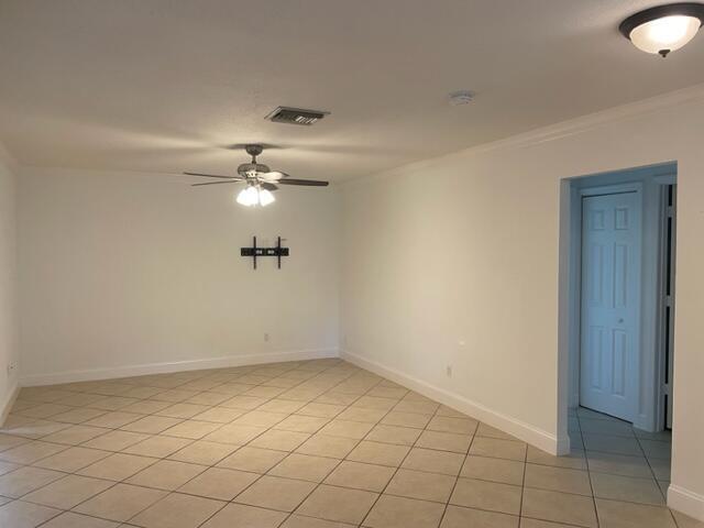 An empty room features white walls, a ceiling fan, and light-colored diagonal tile flooring — 1979 Juno Road, North Palm Beach FL 33408, NORTH PALM BEACH, FL