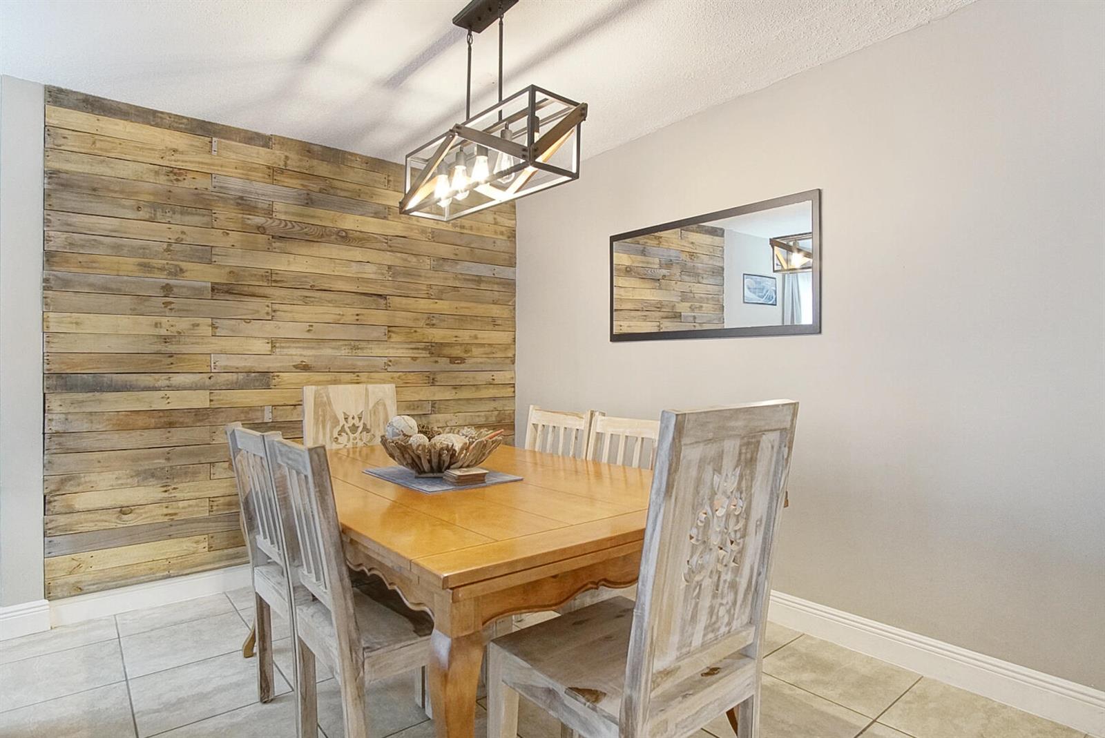 A dining room features a wood-plank accent wall, a rectangular table, and a pendant light — 1002 Avenue E E, Fort Pierce FL 34950, FORT PIERCE, FL