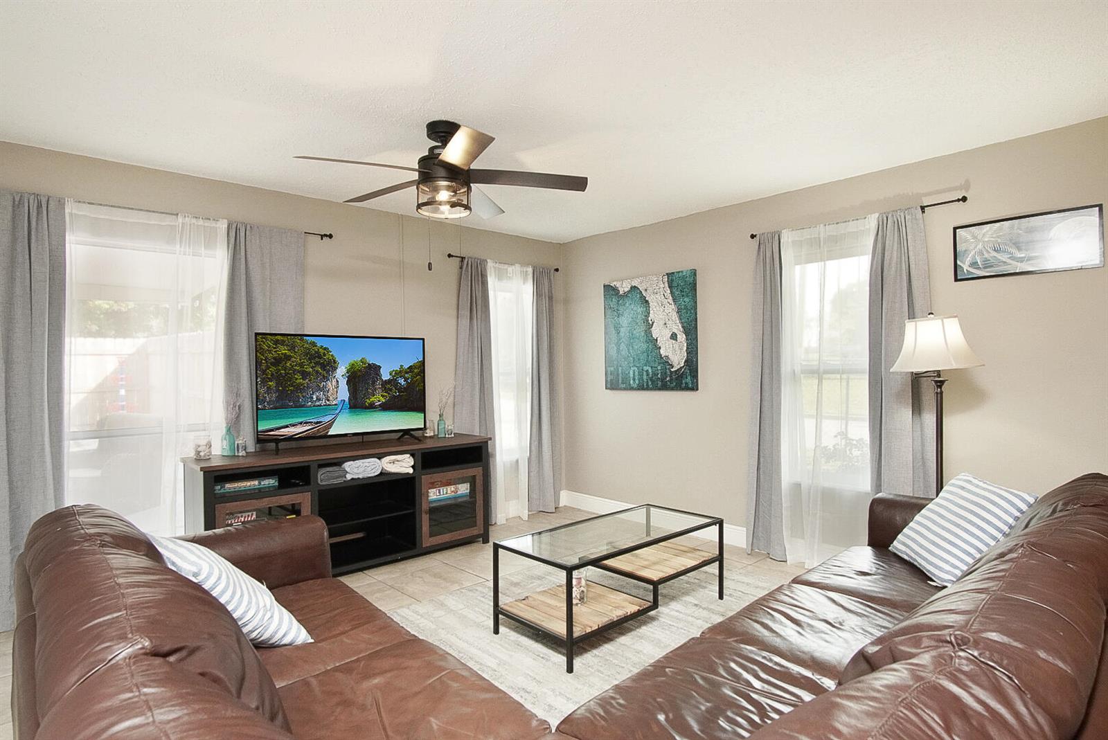 A living room features two brown leather sofas, a glass coffee table, and a television — 1002 Avenue E E, Fort Pierce FL 34950, FORT PIERCE, FL