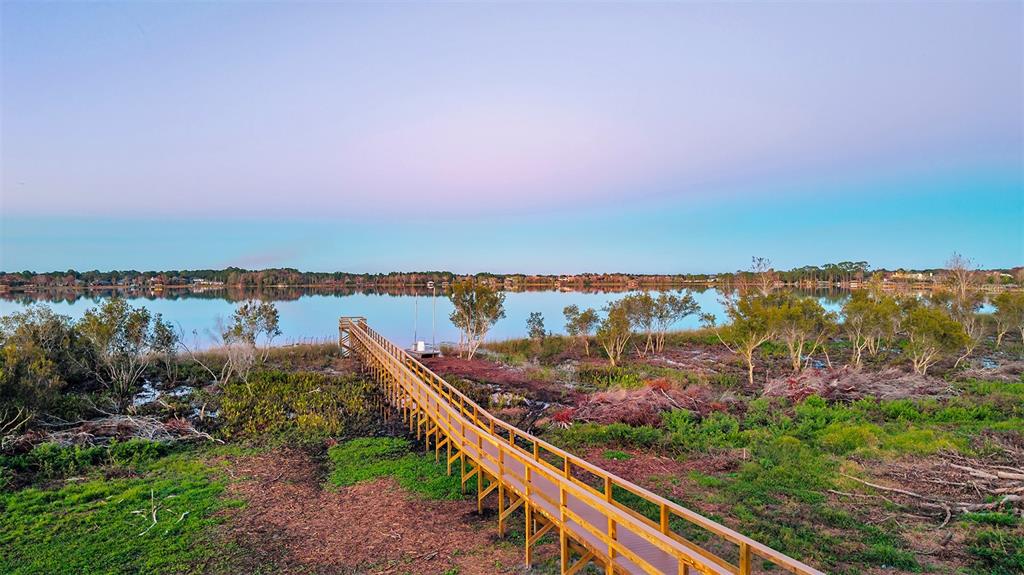 A wooden pier extends from a grassy shoreline into a calm lake at sunset — 19313 LOCHSIDE LANE, MOUNT DORA, FL
