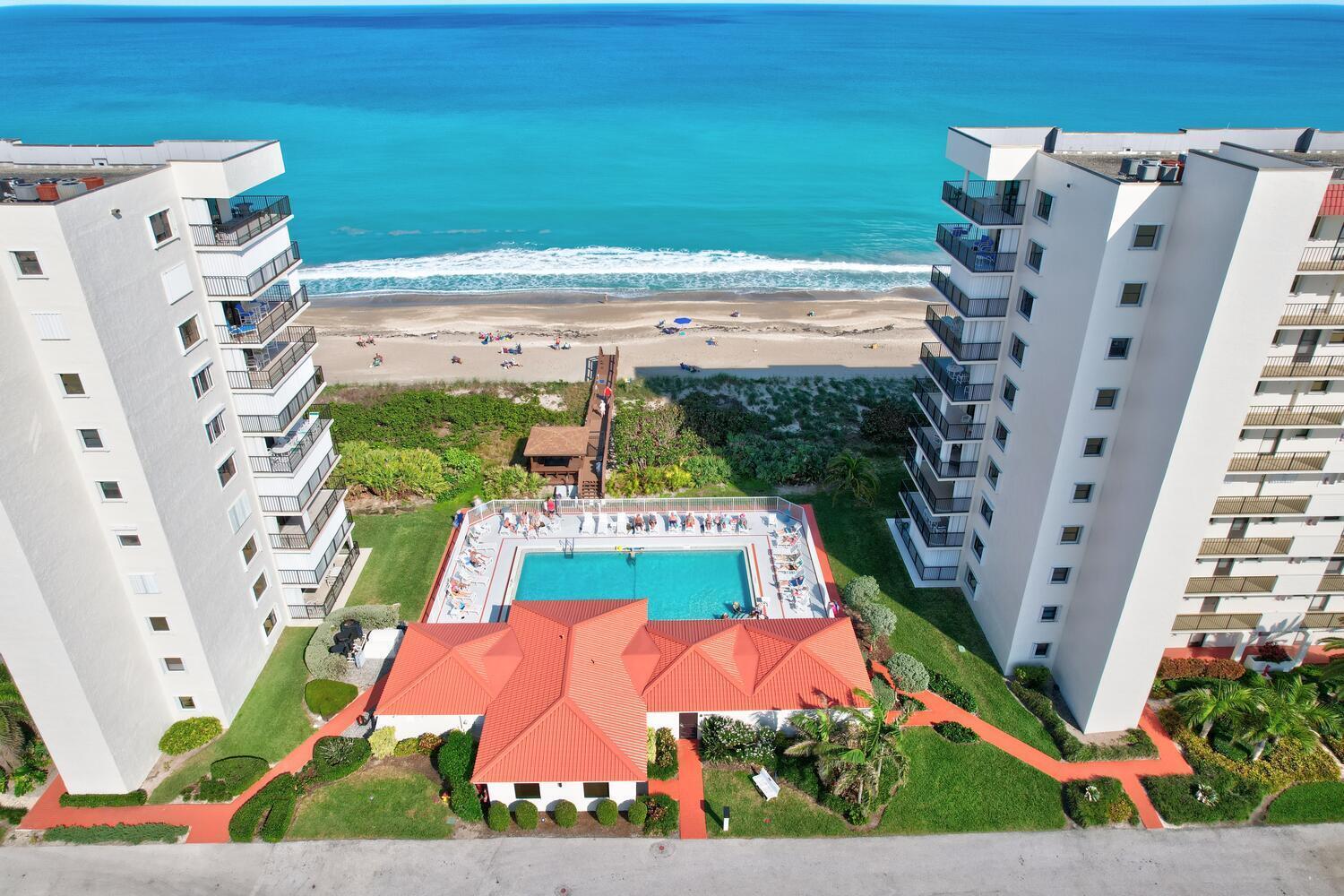 An aerial view shows two high-rise buildings flanking a swimming pool and a beach walkway — 9400 S Ocean Drive # 807, Jensen Beach FL 34957, JENSEN BEACH, FL