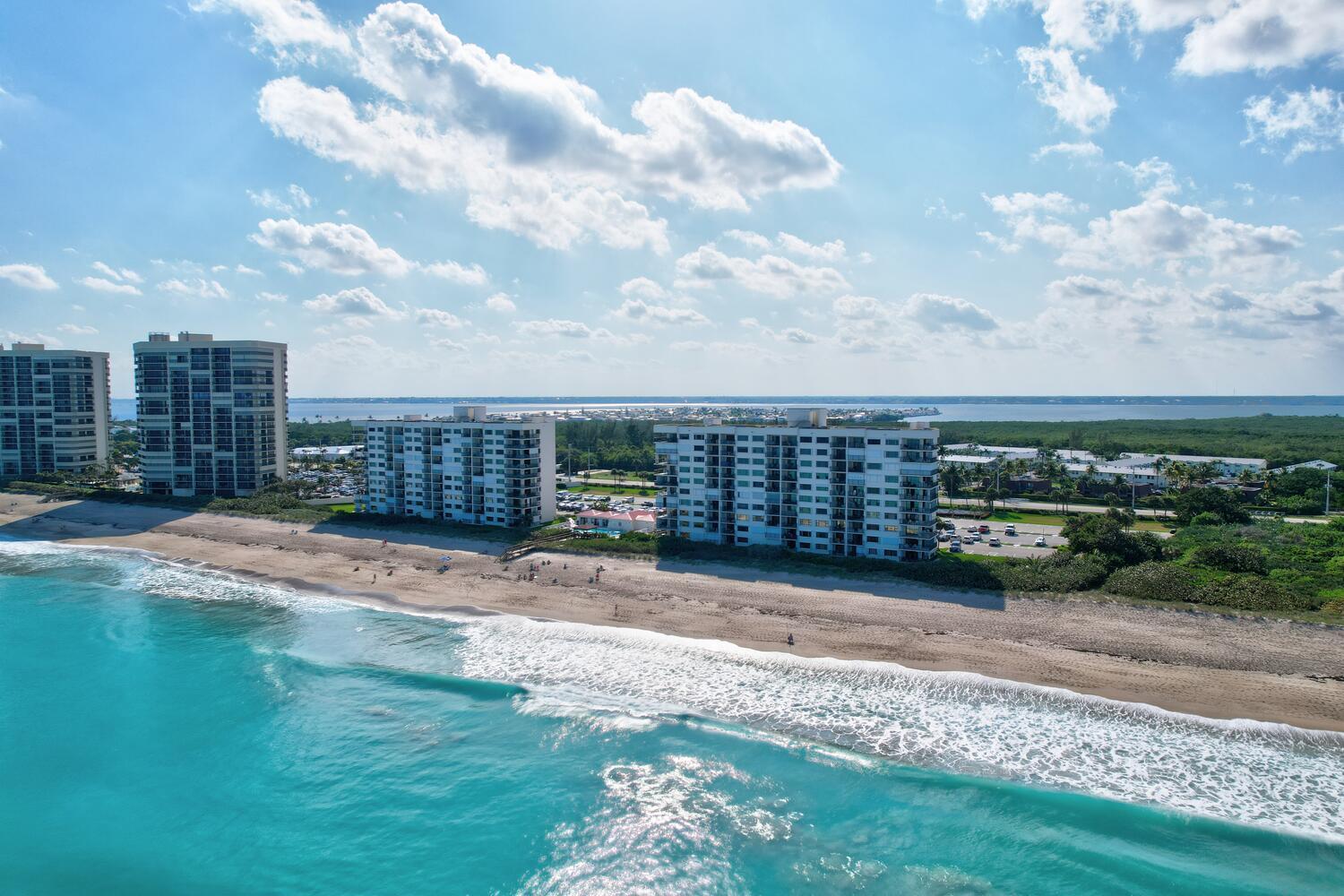 An aerial view shows several tall residential buildings situated along a sandy beach and ocean — 9400 S Ocean Drive # 807, Jensen Beach FL 34957, JENSEN BEACH, FL