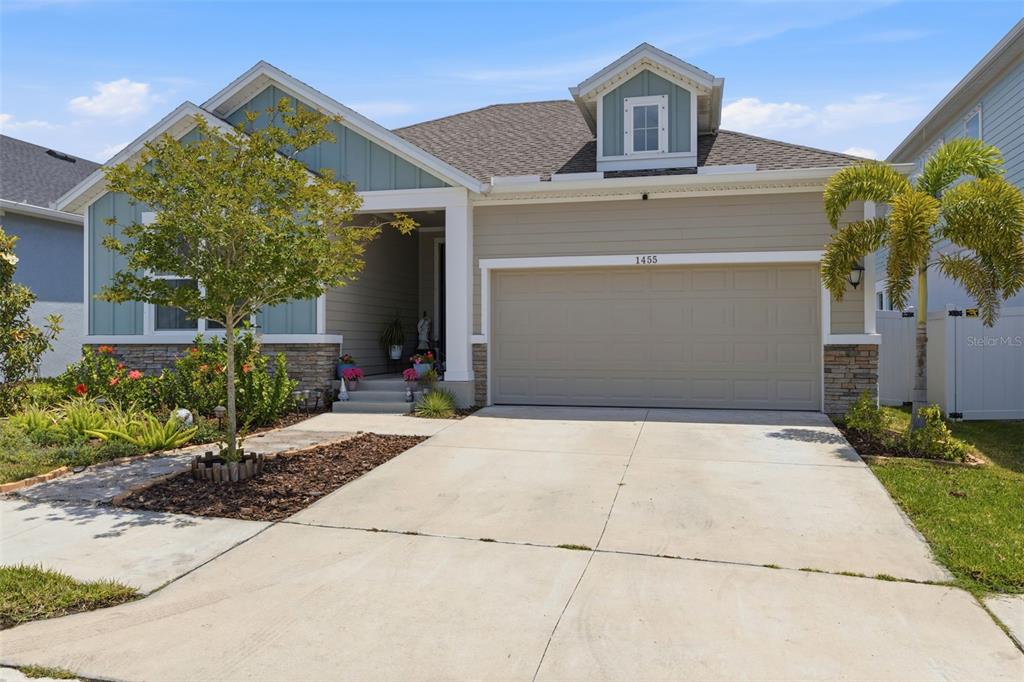A single-story house features a two-car garage, stone accents, and a front-facing dormer window — 1455 GOPHER LOOP, TARPON SPRINGS, FL