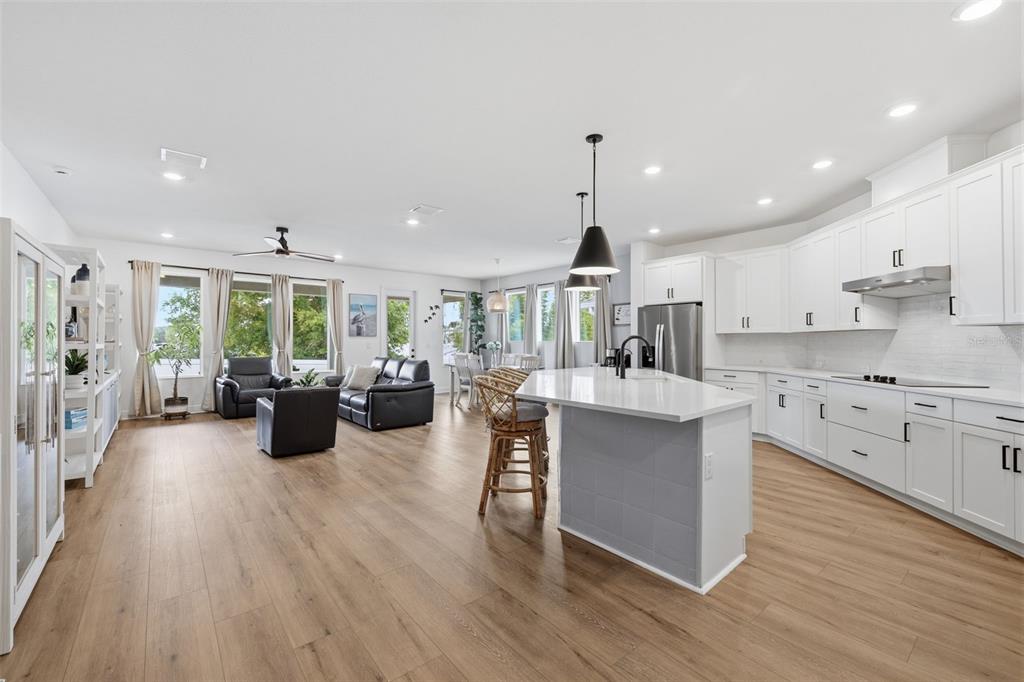 An open-concept kitchen and living area features white cabinetry, a central island, and wood flooring — 1455 GOPHER LOOP, TARPON SPRINGS, FL