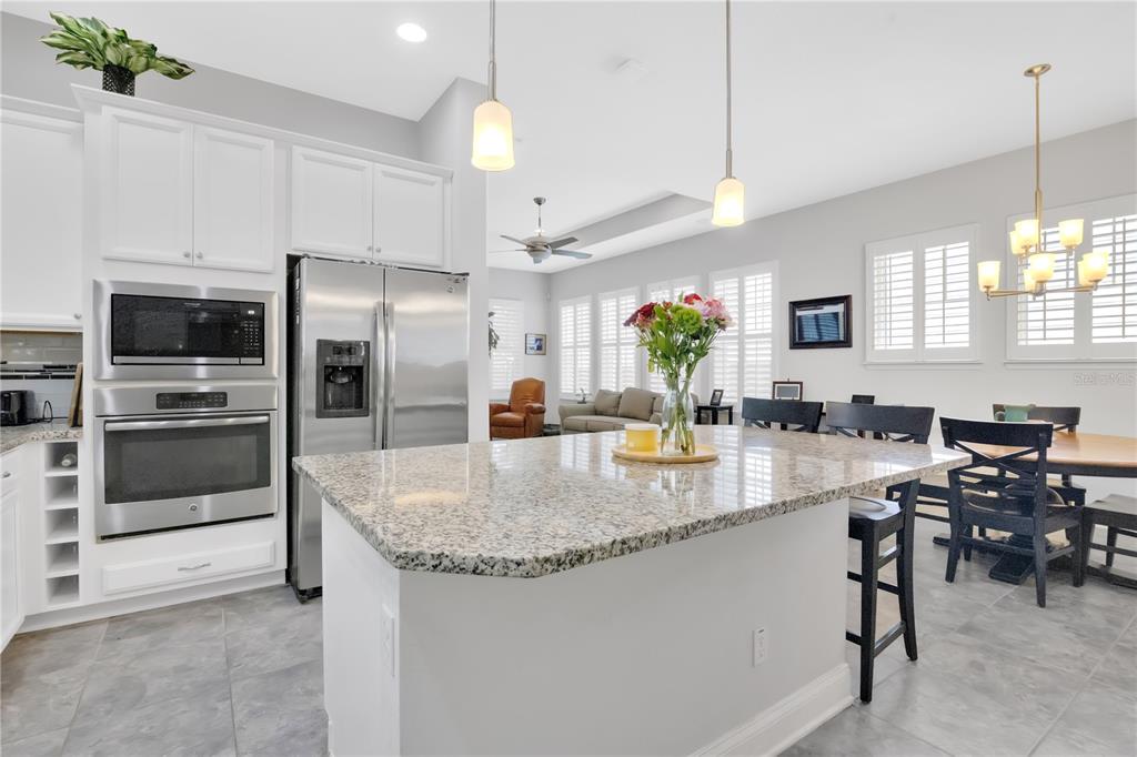 A kitchen with white cabinets, stainless steel appliances, and a granite-topped island — 9189 MERRIFIELD STREET, ORLANDO, FL