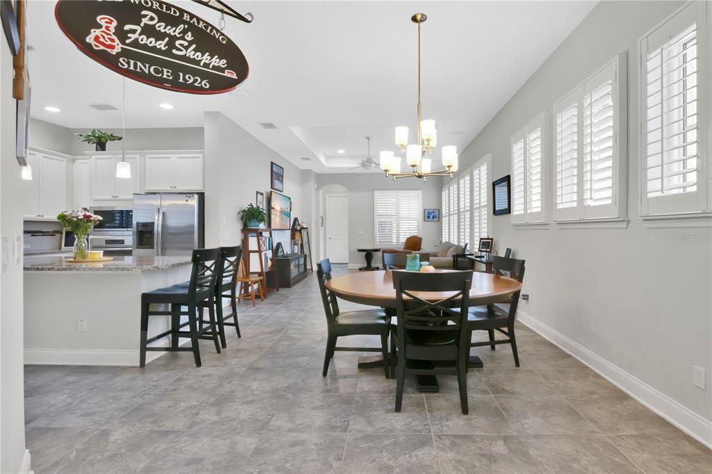 An open-concept kitchen and dining area features tile flooring, white cabinetry, and a chandelier — 9189 MERRIFIELD STREET, ORLANDO, FL