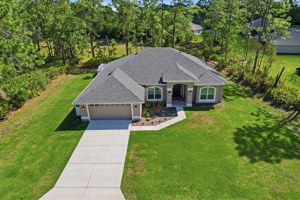 An aerial view of a single-story house with a gray roof and a concrete driveway — 3 STOKESIA COURT, HOMOSASSA, FL