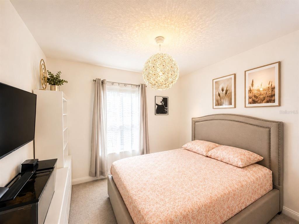 A bedroom features a gray upholstered headboard, a patterned bedspread, and a spherical pendant light — 1200 WYCLIFFE WAY, ST CLOUD, FL