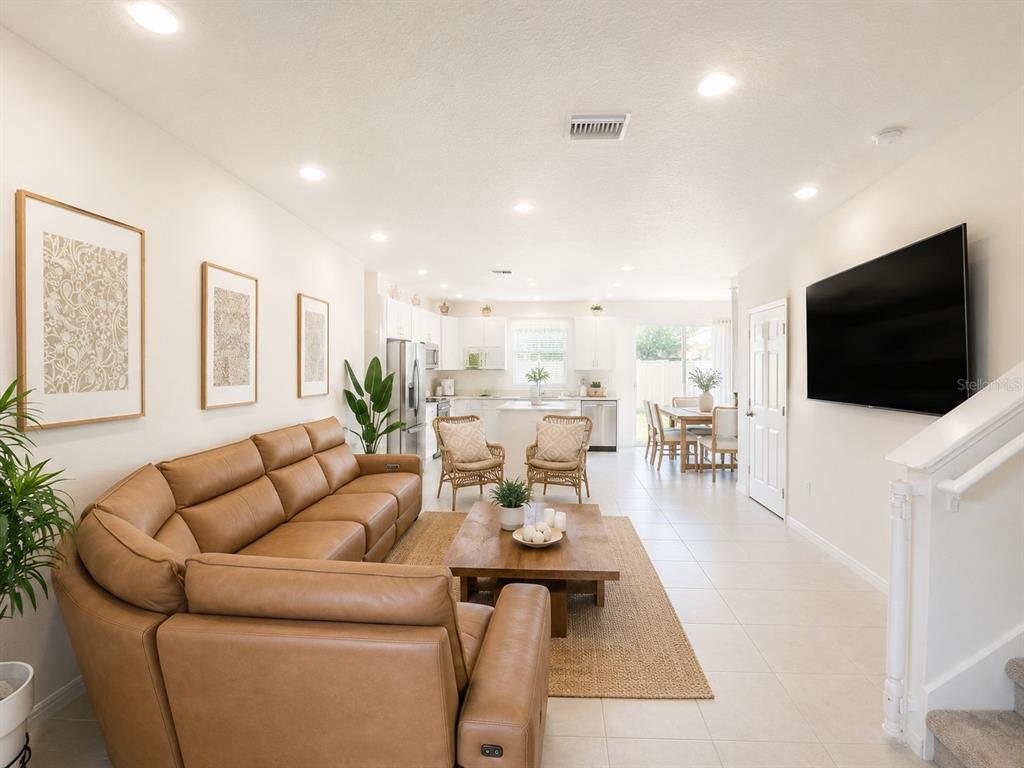 A living room with a tan leather sectional, wooden coffee table, and open-concept kitchen — 1200 WYCLIFFE WAY, ST CLOUD, FL