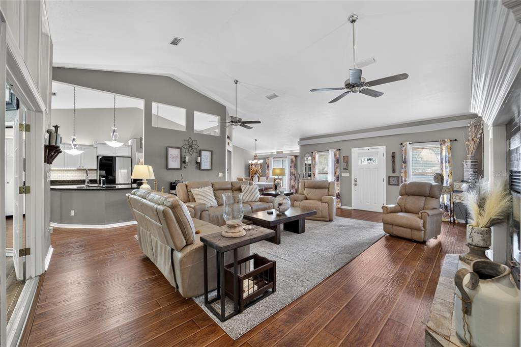 A spacious living room with vaulted ceilings, hardwood floors, and an open-concept kitchen — 4823 SE 14TH STREET, OCALA, FL