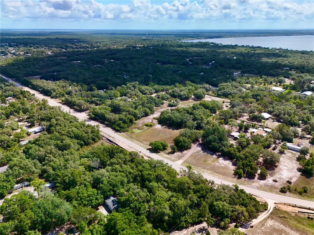An aerial view shows a paved road winding through a wooded area with scattered houses — 3175 WALK IN WATER ROAD, LAKE WALES, FL
