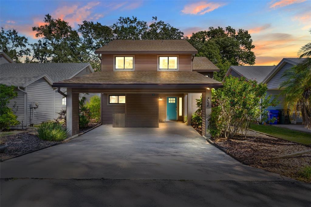 A two-story house with brown siding, a covered carport, and a bright blue front door — 3576 RAINTREE WAY, LAKELAND, FL