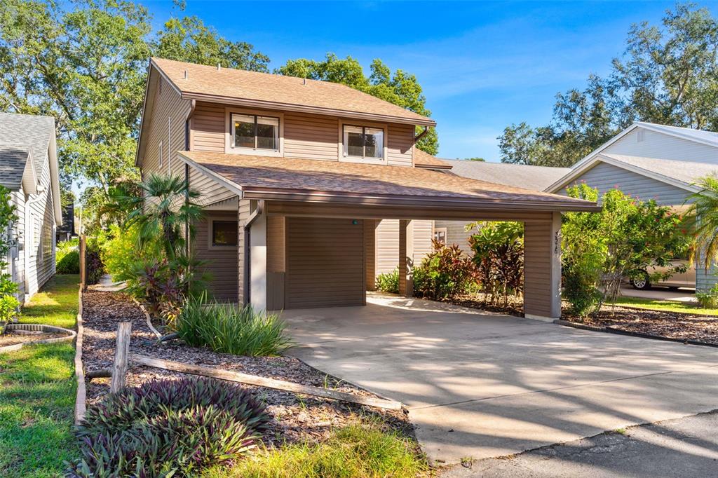 A two-story house with brown siding, a shingled roof, and an attached carport — 3576 RAINTREE WAY, LAKELAND, FL