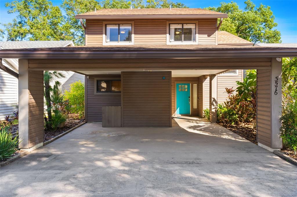 A two-story house features a large covered carport and a bright blue front door — 3576 RAINTREE WAY, LAKELAND, FL