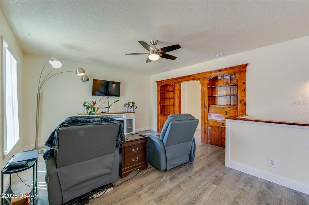 A living room features two gray recliners, a floor lamp, and a wooden built-in bookshelf — 243 N PENINSULA DRIVE, DAYTONA BEACH, FL