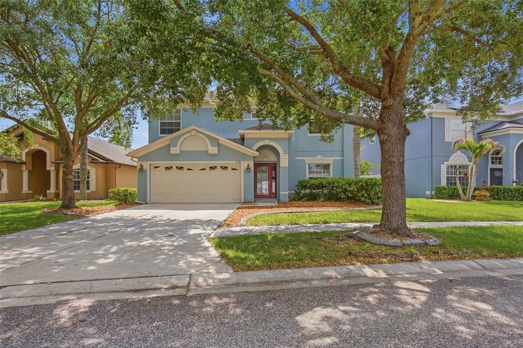 A two-story blue house with a two-car garage and a red front door — 18318 HOLLAND HOUSE LOOP, LAND O LAKES, FL