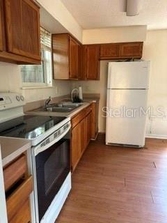 A kitchen features wood cabinets, a white refrigerator, and a stainless steel stove — 248A S CLAYTON STREET Apt A, MOUNT DORA, FL