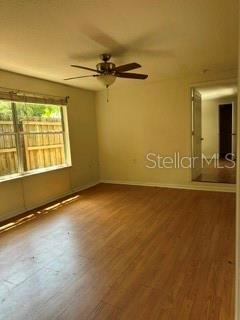 An empty room with light wood-look flooring, a ceiling fan, and a large window — 248A S CLAYTON STREET Apt A, MOUNT DORA, FL