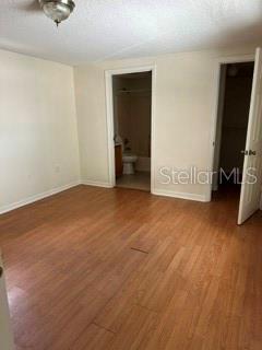 An empty room with wood-look flooring, a ceiling light, and doorways leading to a bathroom — 248A S CLAYTON STREET Apt A, MOUNT DORA, FL