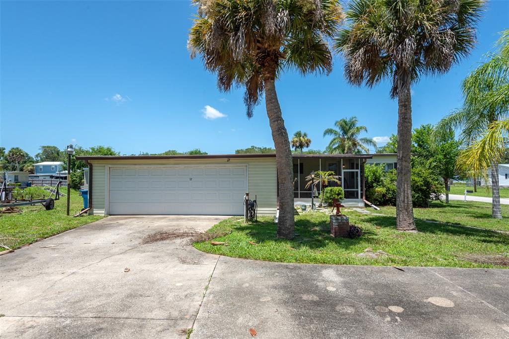 A single-story house with a white garage door, a screened porch, and two tall palm trees — 110 CHARLES STREET, EDGEWATER, FL