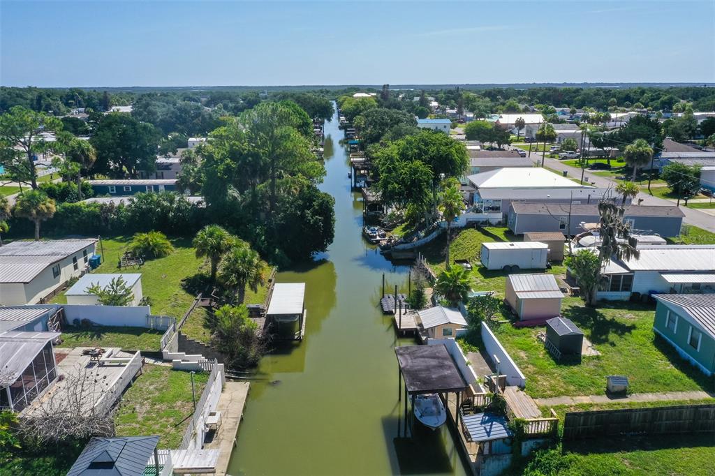An aerial view shows a narrow canal lined with residential properties, boat docks, and trees — 110 CHARLES STREET, EDGEWATER, FL