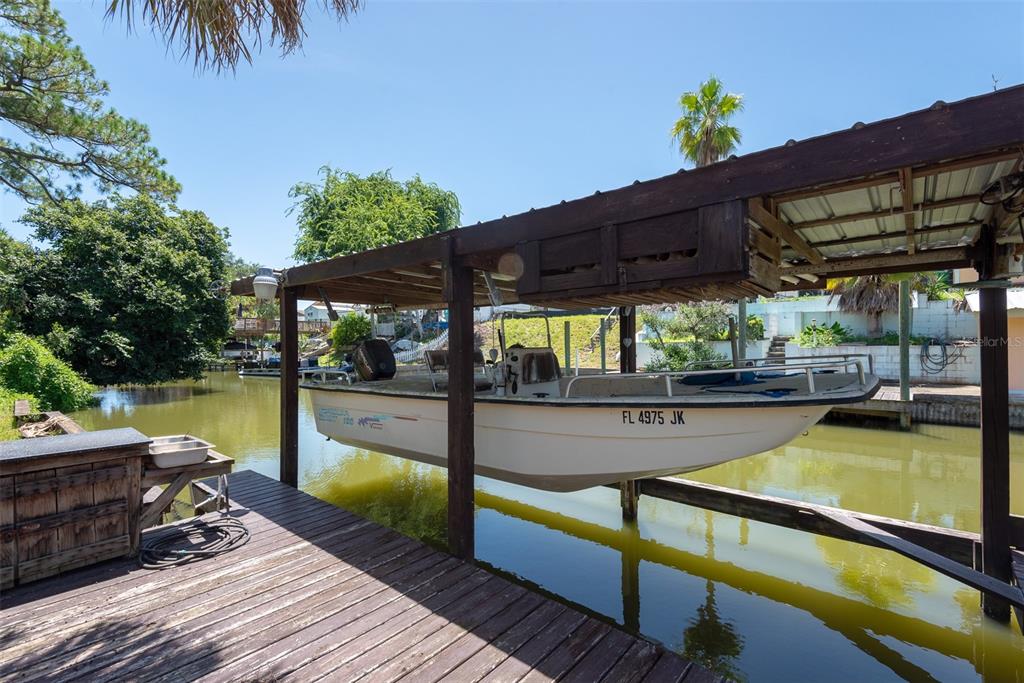 A boat sits on a lift under a wooden cover next to a wooden dock — 110 CHARLES STREET, EDGEWATER, FL
