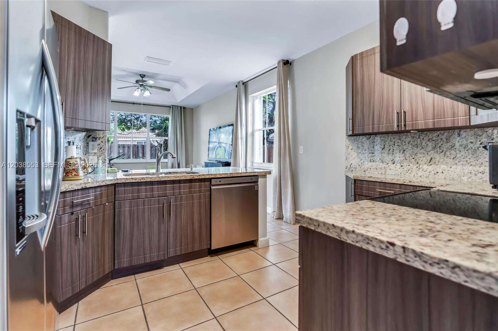 A kitchen features wood-grain cabinets, granite countertops, stainless steel appliances, and beige tile flooring — 16728 SW 36th St, Miramar FL 33027, MIRAMAR, FL