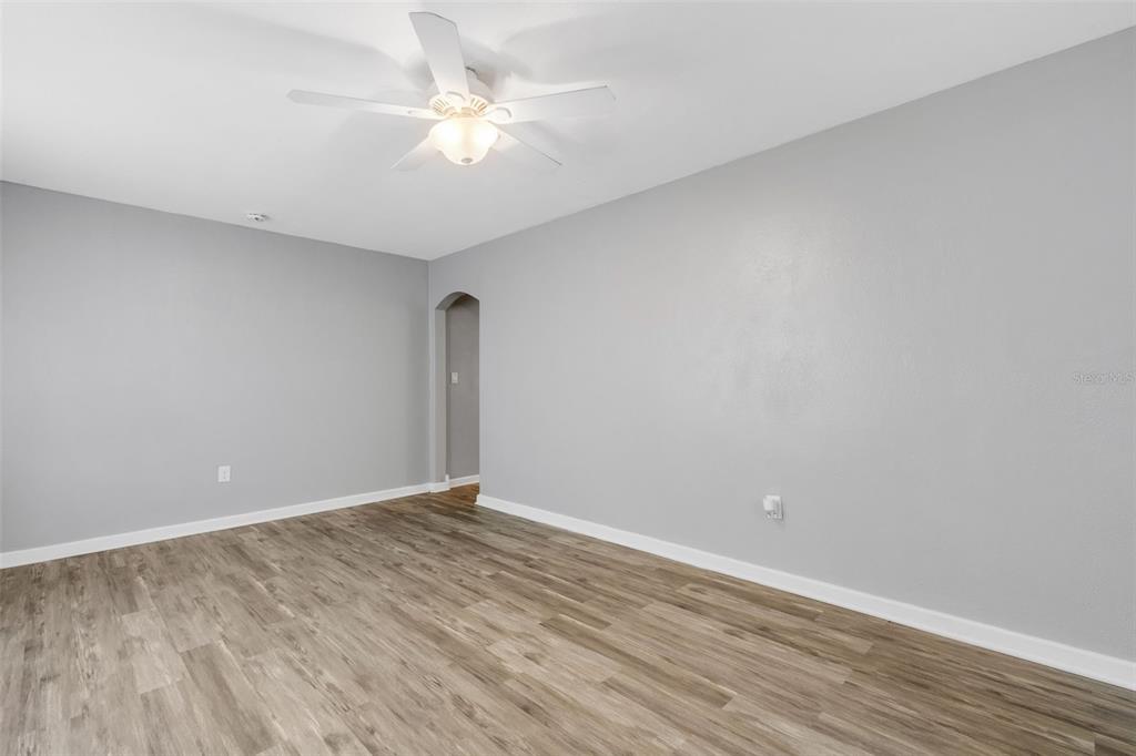 An empty room features gray walls, wood-look flooring, and a ceiling fan — 1608, 1610, 1612 11TH STREET W, BRADENTON, FL