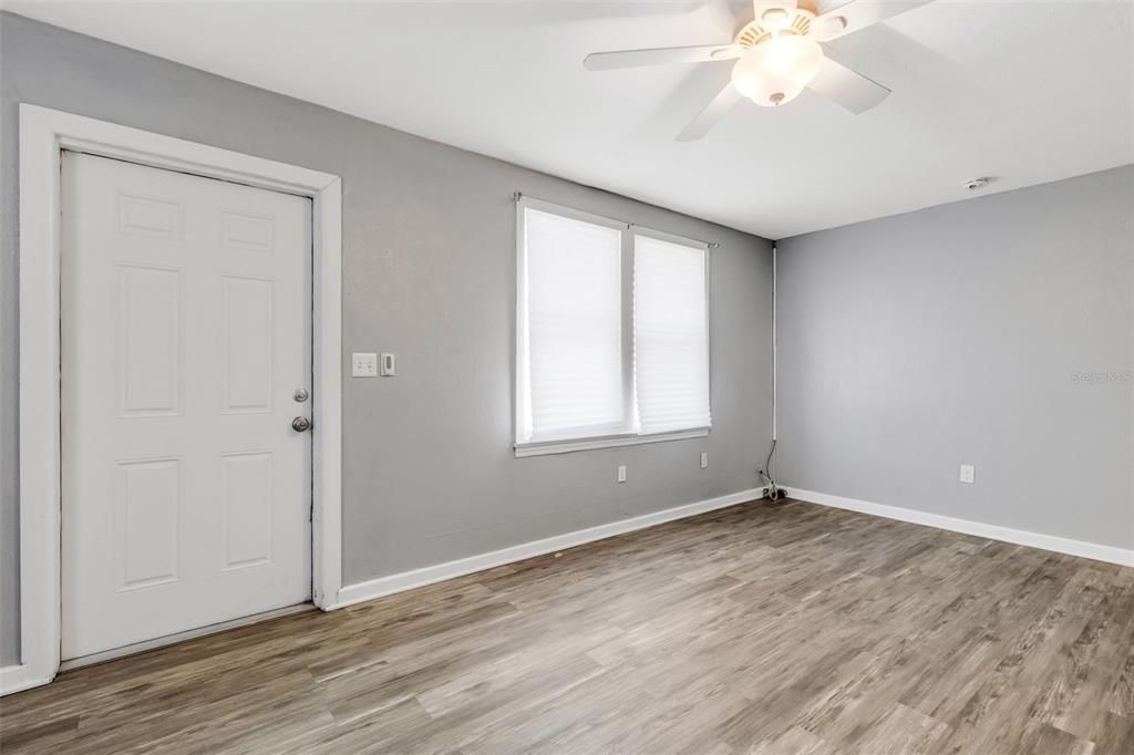 A room with gray walls, wood-look flooring, a white door, and a ceiling fan — 1608, 1610, 1612 11TH STREET W, BRADENTON, FL