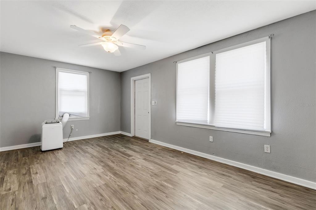 A room with gray walls, wood-look flooring, a ceiling fan, and a portable air conditioner — 1608, 1610, 1612 11TH STREET W, BRADENTON, FL