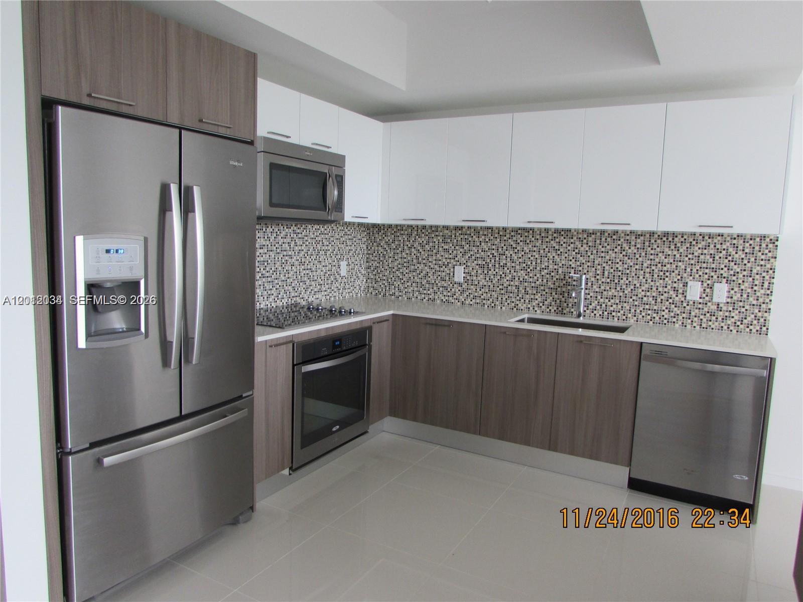 A modern kitchen features stainless steel appliances, two-toned cabinetry, and a mosaic tile backsplash — 5300 Paseo Blvd # 405, Doral FL 33166, DORAL, FL