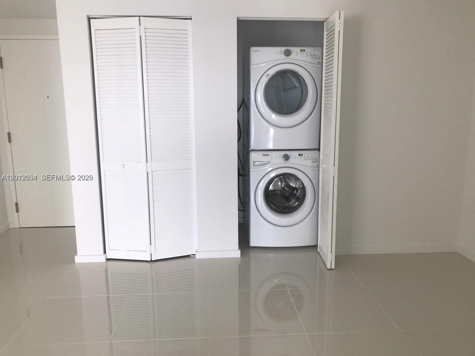A laundry closet with a stacked washer and dryer sits in a room with tile floors — 5300 Paseo Blvd # 405, Doral FL 33166, DORAL, FL