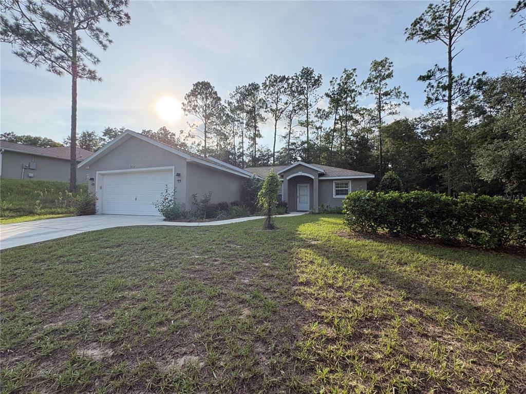 A single-story house with a white garage door, a front entrance, and a grassy yard — 9832 SW 196TH AVENUE ROAD, DUNNELLON, FL