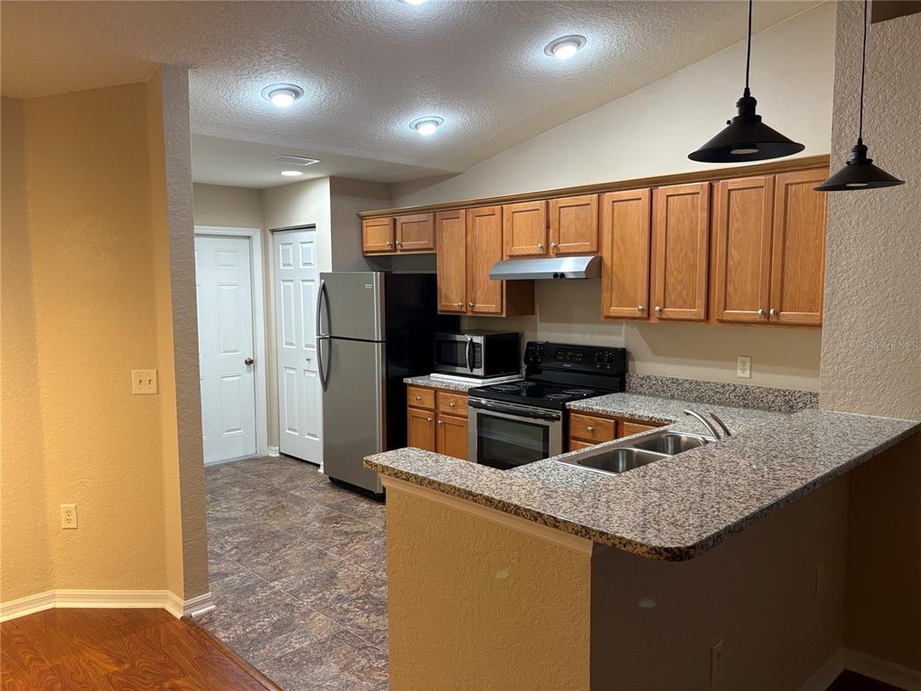 A kitchen with oak cabinets, granite countertops, stainless steel appliances, and a breakfast bar — 9832 SW 196TH AVENUE ROAD, DUNNELLON, FL