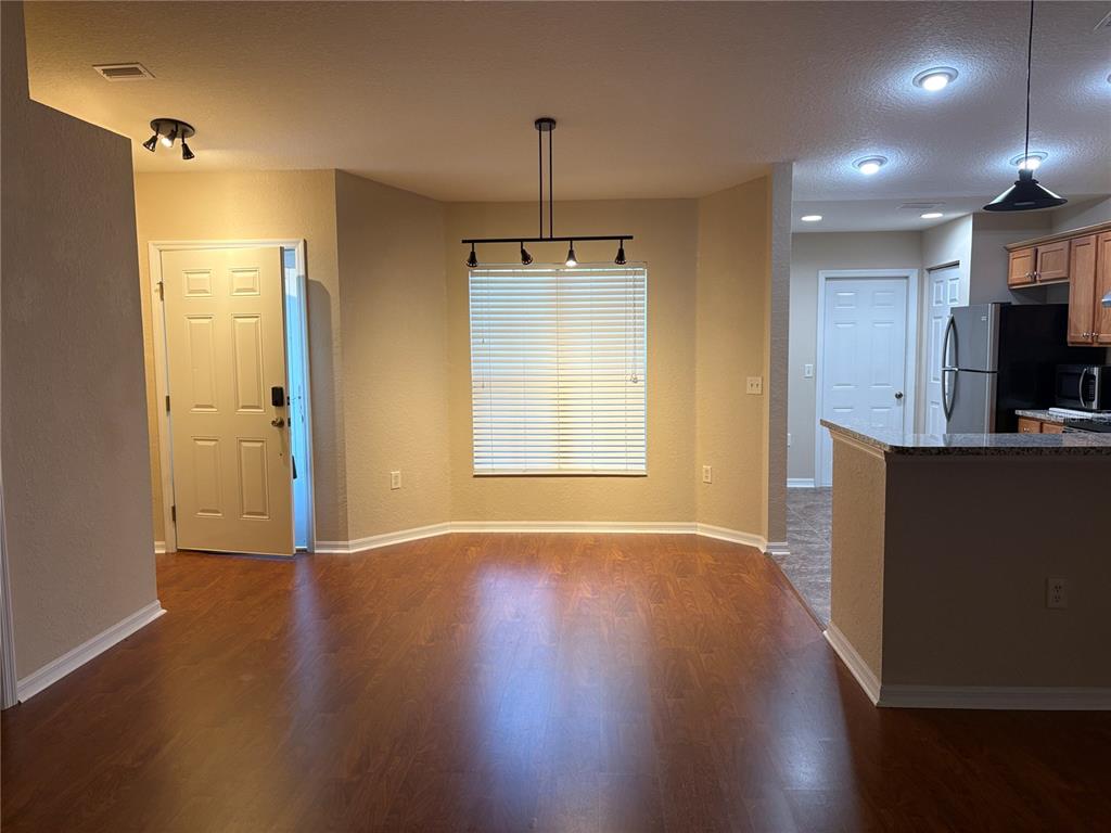 An open dining area with wood-look flooring, a window with blinds, and a kitchen counter — 9832 SW 196TH AVENUE ROAD, DUNNELLON, FL