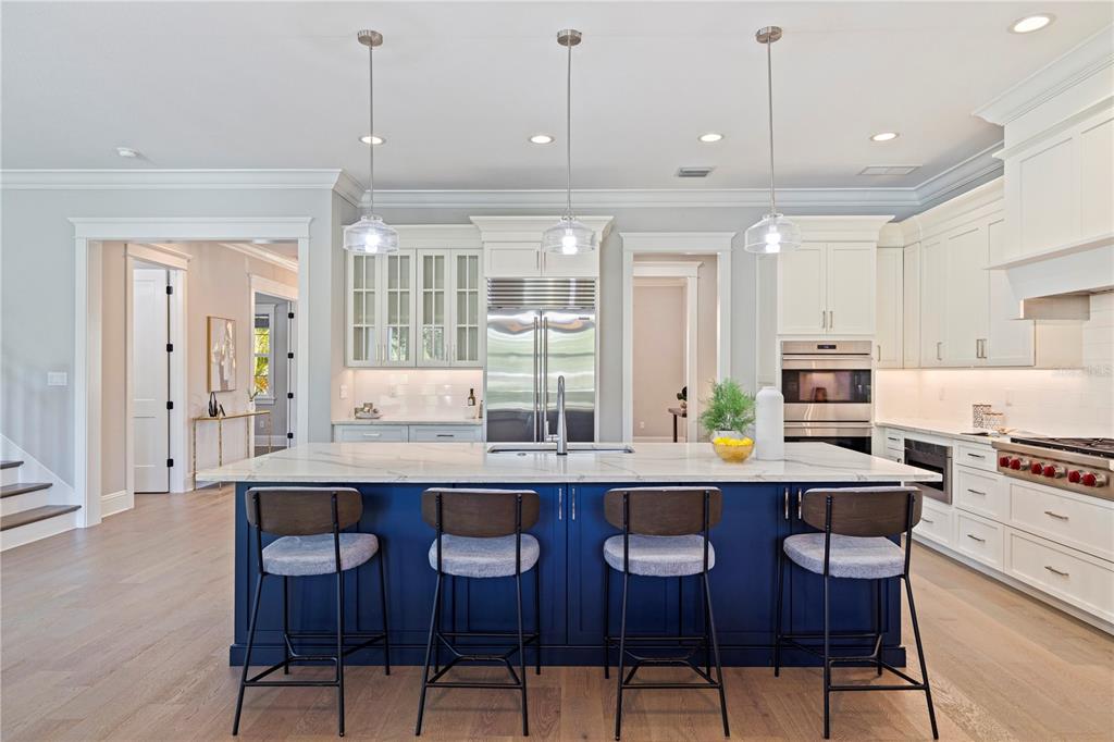 A kitchen features a large blue island with four stools and white cabinetry — 1001 CORDOVA BOULEVARD NE, ST PETERSBURG, FL