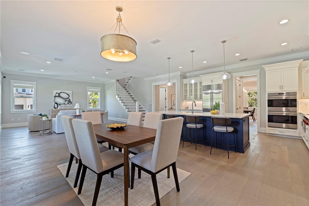 An open-concept kitchen and dining area features a blue island, wood floors, and white cabinetry — 1001 CORDOVA BOULEVARD NE, ST PETERSBURG, FL