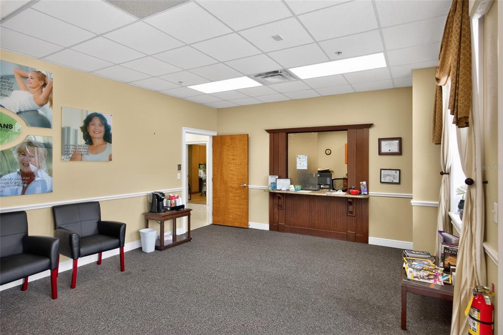 A waiting room features black chairs, a reception window, and beige walls with framed photos — 733 COUNTY ROAD 466, LADY LAKE, FL
